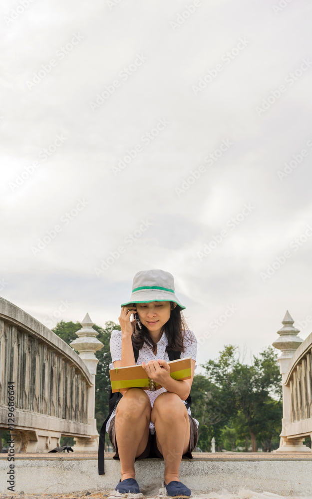 Happy travel woman reading book on old concrete bridge
