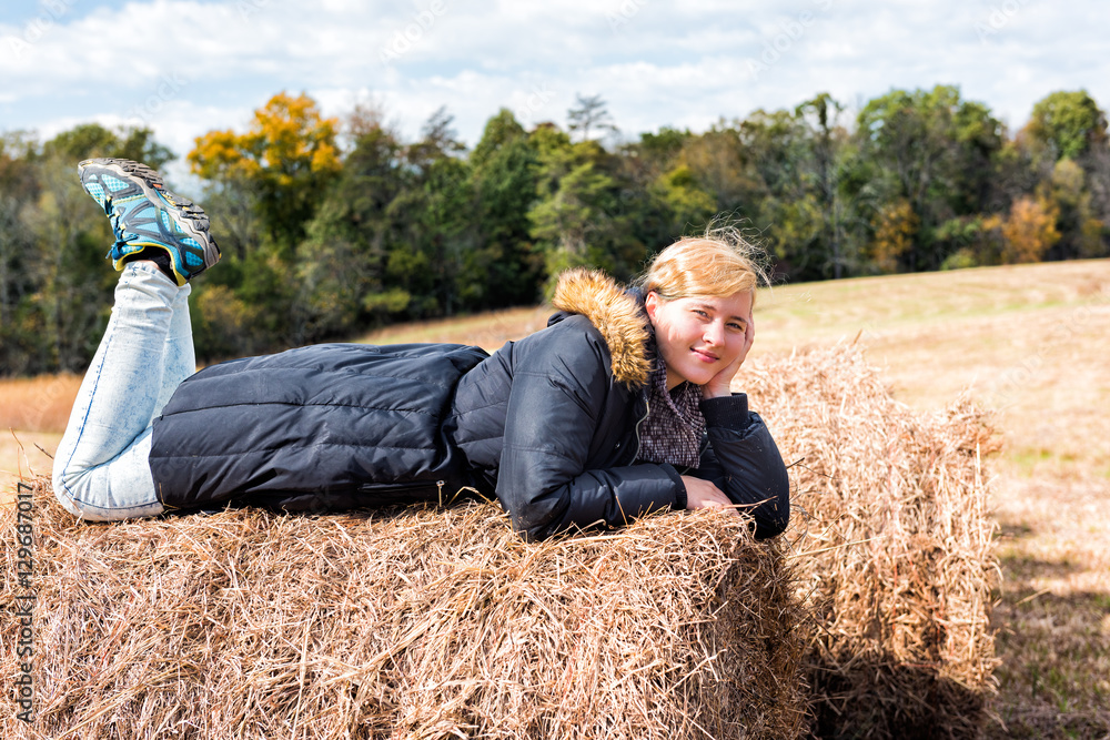 Young woman lying down on hay roll bale Young woman lying down on hay roll bale