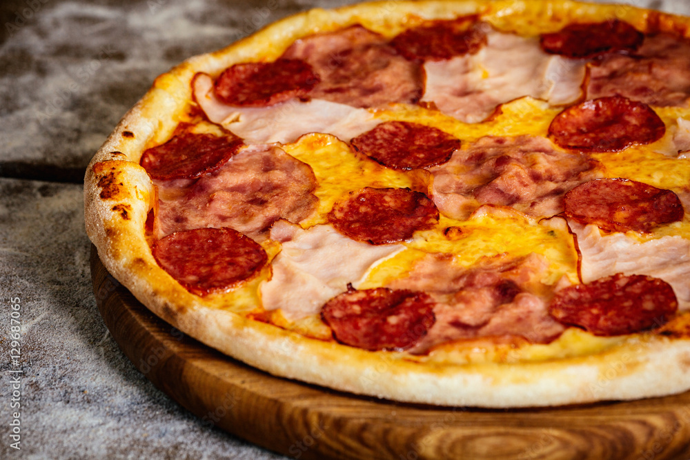 Pizza with ham and sausages on wood background Pizza with ham and sausages on wood background