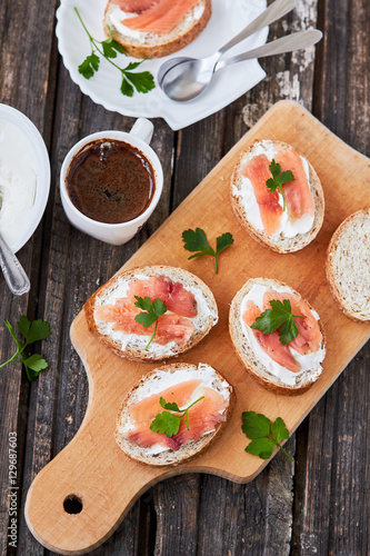  Smoked salmon and cream cheese sandwich and a cup of coffee on a wooden surface. top view. vertical