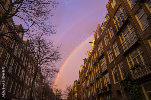 Rainbow on a purple sky over street buildings in Amsterdam