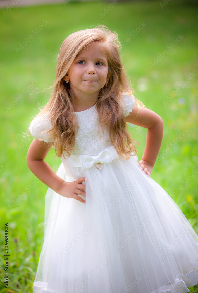 Little girl on the lawn in a white dress
