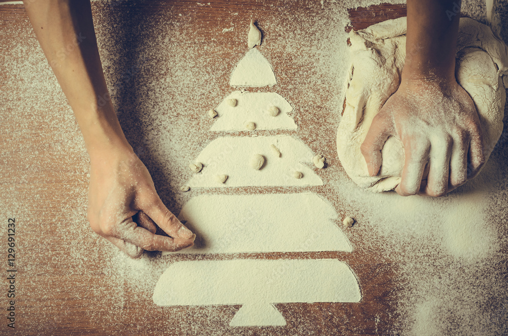 Fototapeta Female hands pressing dough and make the Christmas cookies