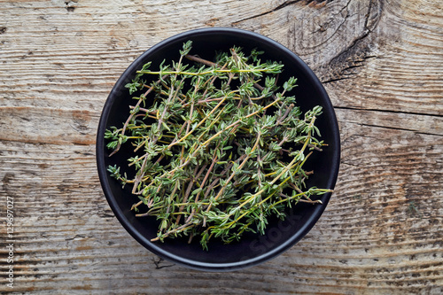 Bowl of thyme on wooden table, from above