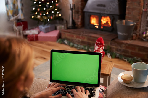 Woman Using Laptop In Room Decorated For Christmas