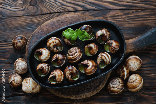 Baked snails with garlic butter in a rustic wooden setting