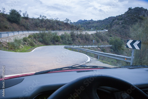 Driving by narrow mountain curvy road at sunset