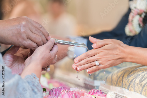 Close-up of water being poured on the hands of the bride during a traditional Thai wedding ceremony. 