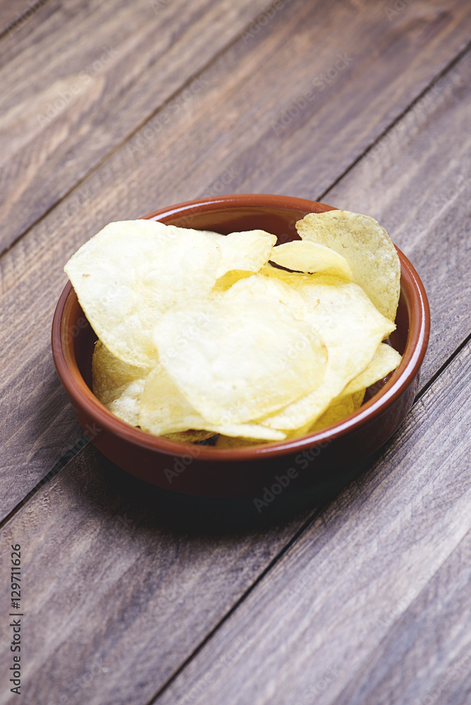 A dish with chips standing on dark gray colored wooden table. Vertical studio shot A dish with chips standing on dark gray colored wooden table. Vertical studio shot