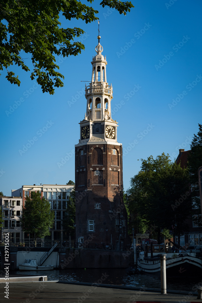 The 1606 Montelbaanstoren tower on bank of the canal Oudeschans in Amsterdam, Netherlands. The original tower was built in 1516 as part of the Walls of Amsterdam.