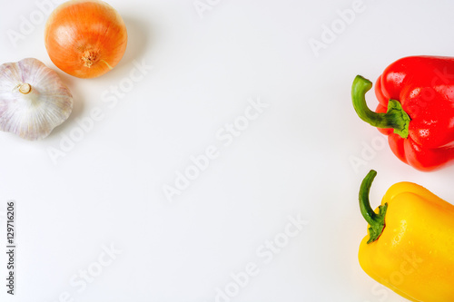 Red and yellow peppers, onion and garlic on a white background, top view