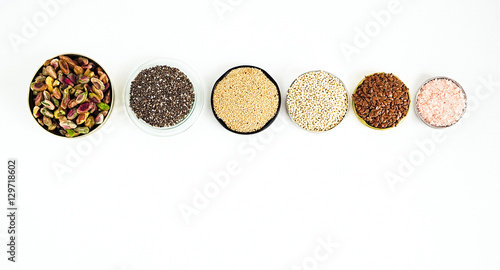 Various superfoods on a white background. Pistachio nuts, chia seeds, amaranth, quinoa, flex seeds, rose salt. Copy space for text
