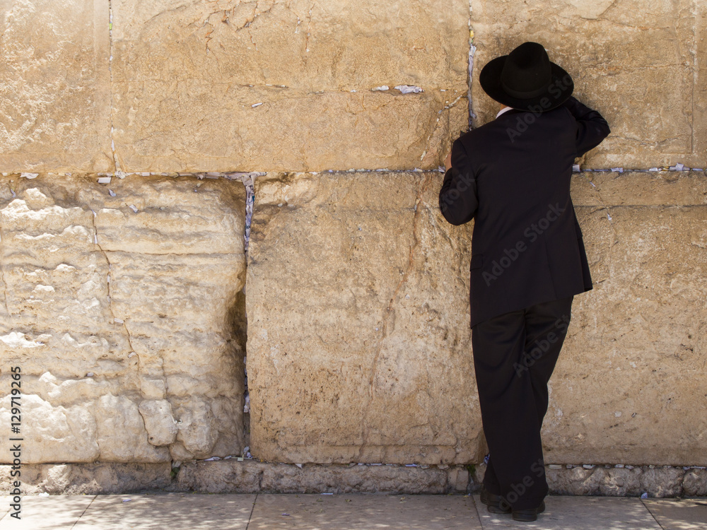 orthodox man with black clothes and hat praying at the Wailing Wall, Jerusalem