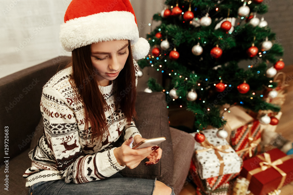 Smiling, beautiful brunette woman in red santa claus hat and whi Smiling, beautiful brunette woman in red santa claus hat and whi