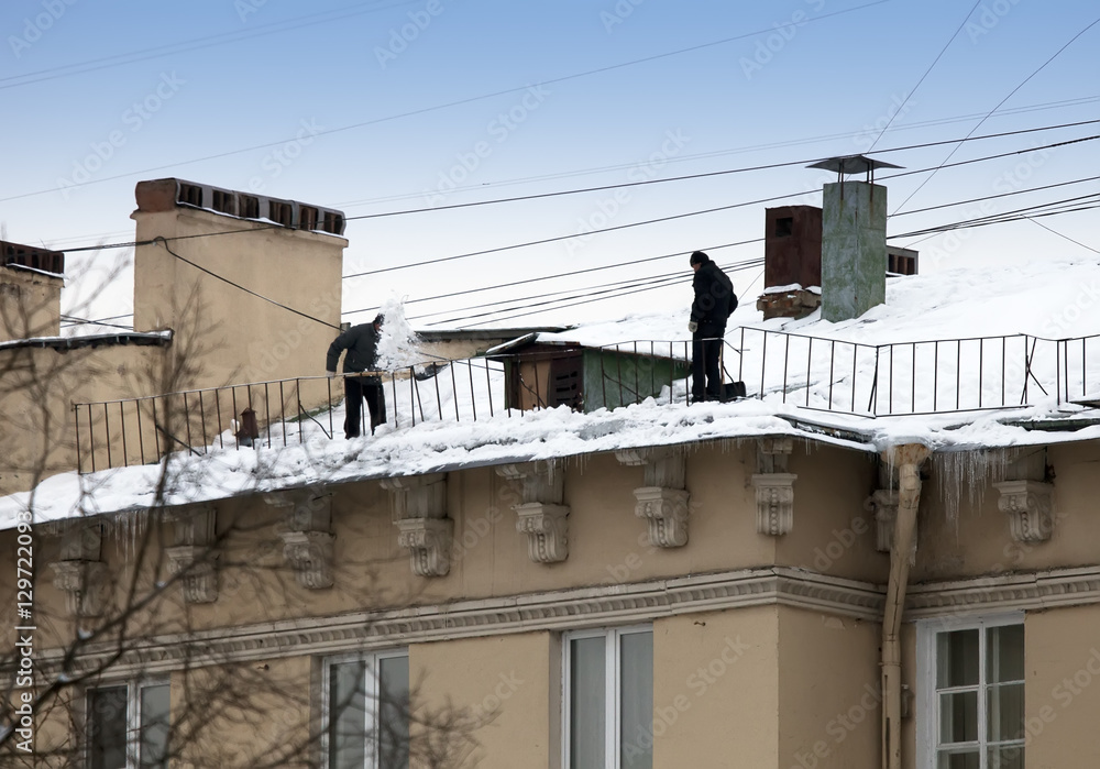 Take off the snow and icicles from the roof. Working cleaning work without insurance. Russia, St. Petersburg Take off the snow and icicles from the roof. Working cleaning work without insurance. Russia, St. Petersburg
