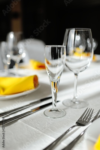 beautiful empty wine glasses and yellow napkin on a decorated table close-up.