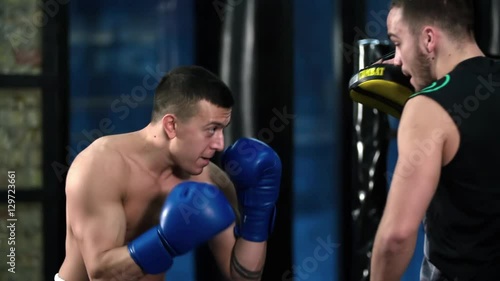 Boxer training uppercut punches in boxing club HD slow motion video. Fighter practices blows with trainer punch mitts. Combat sport technique