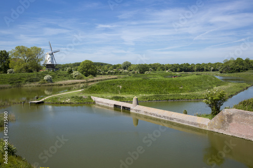 Typical Dutch countryside landscape with a canal, fortified wall and a windmill