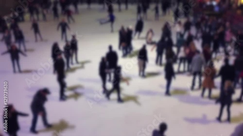 Abstract defocus view of ice skaters going around a winter rink in slow motion in Midtown Manhattan, New York City
