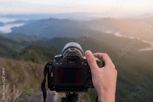 Photographer adjusts camera before shooting photo on mountain. Landscape photographer and hiker concept. © structuresxx