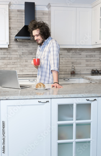 Man Eating Breakfast Using Laptop, Man in kitchen drinking coff