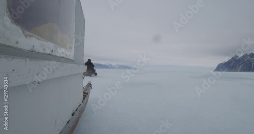 Next to komatik speeding over sea ice on stormy day photo