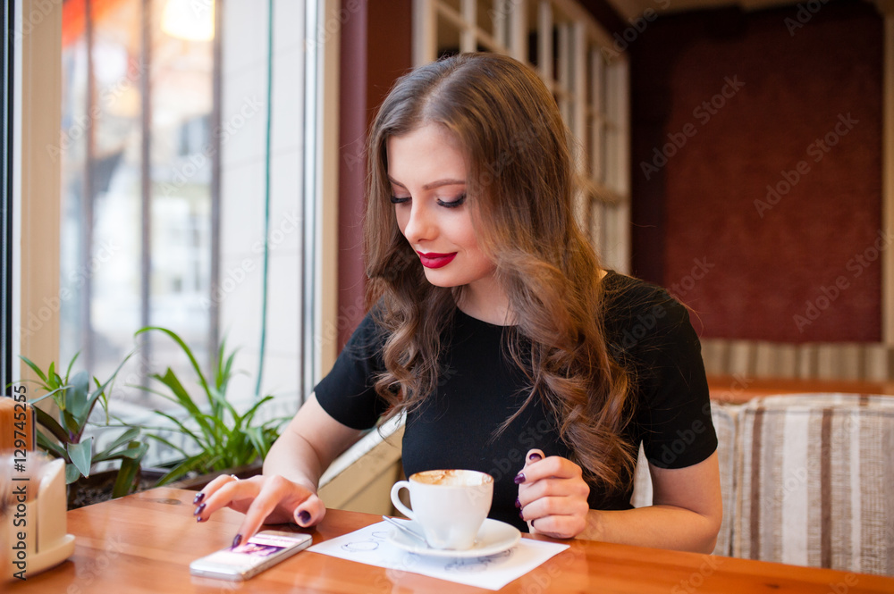 Beautiful girl drinking coffee and looking in the phone Beautiful girl drinking coffee and looking in the phone