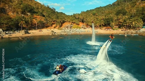 Aerial: Two men flying on flyboard near the beach.