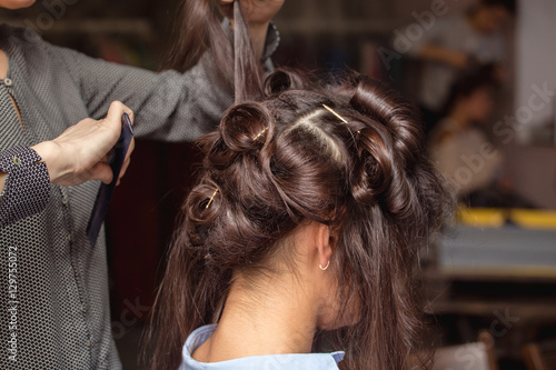 Hairdresser making a braid on long brunette hair in barber salon