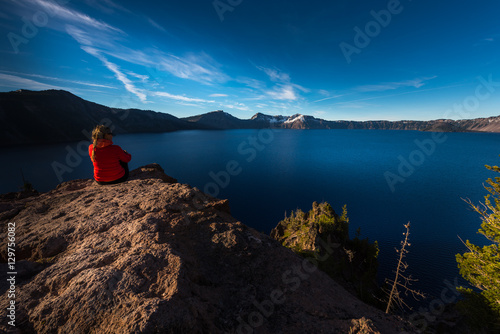 Woman Sitting on the Edge of a Cliff looking at Crater Lake Oreg
