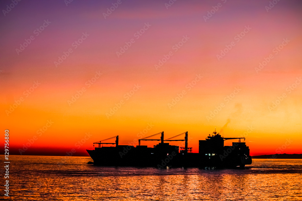 Big cargo ship silhouette leaving harbor.