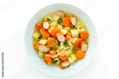 Close-up of a homemade Frankfurter Sausage Stew in a blue soup plate isolated on white background. 