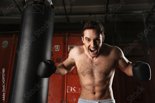 Screaming agressive boxer training in a gym with punchbag © Drobot Dean