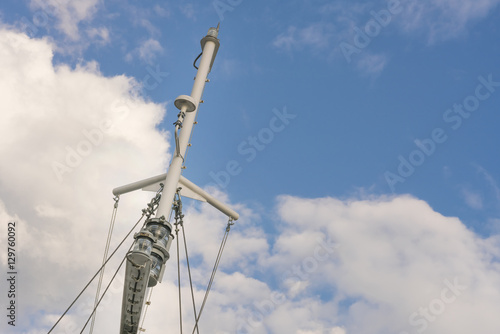 Grey mast on a blue sky with clouds