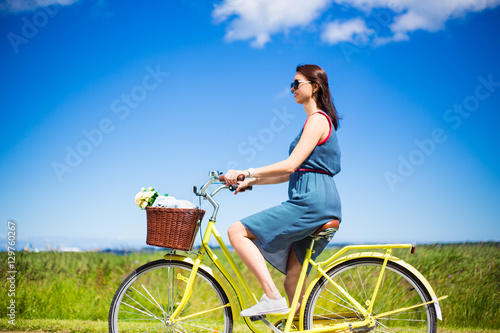 side view of beautiful woman riding vintage bicycle in countrysi photo