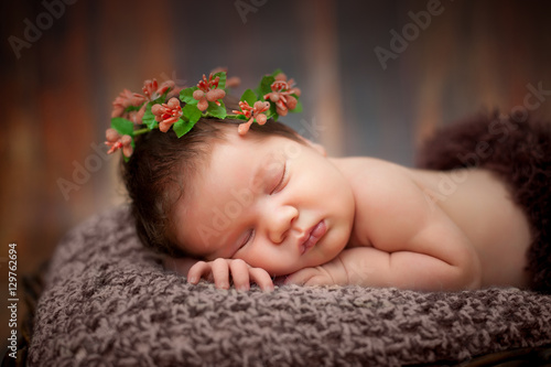 beautiful newborn sleeping baby girl in a wicker basket on a wooden background
