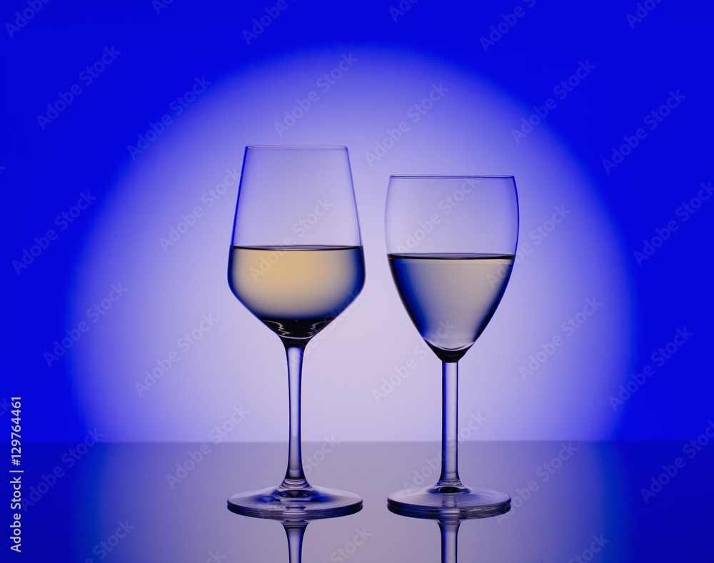 Wineglass with white wine on blurred blue  background