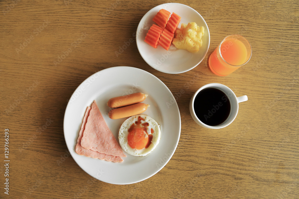 Set of american breakfast on table, fried egg, ham, and sausage Set of american breakfast on table, fried egg, ham, and sausage