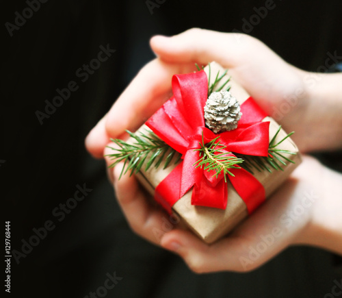 Christmas gift in the children's hands on the dark background. Congratulations to the new year, gift presentation.