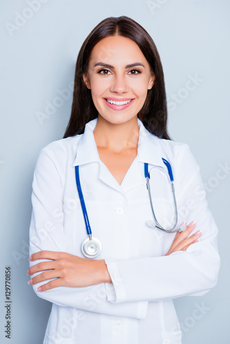 Portrait of pretty female doctor with beaming smile and crossed