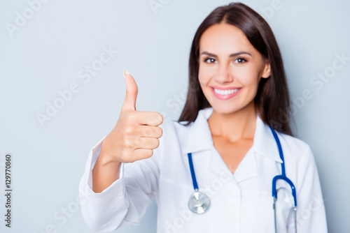Pretty smilind doctor in white uniform showing thumb up