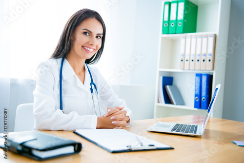 Portrait of cheerful happy female doctor with laptop on consulta