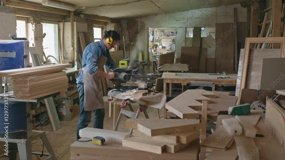 PAN with slow motion of concentrated woodworker standing in workshop and cutting boards with bandsaw PAN with slow motion of concentrated woodworker standing in workshop and cutting boards with bandsaw