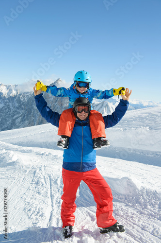 Smiling little boy with father in the mountains during ski holiday