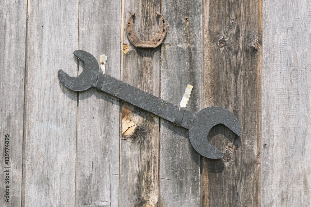 Wrench and horseshoe hanging on an old wooden fence Wrench and horseshoe hanging on an old wooden fence