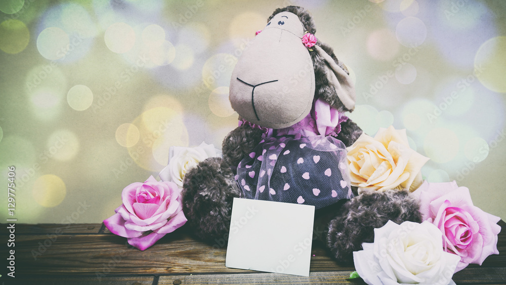 plush lamb and pink roses and a wooden background, a note on the plush lamb and pink roses and a wooden background, a note on the