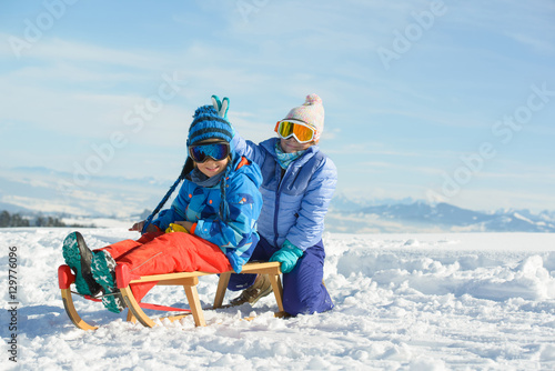Happy children has fun with wooden sled in the mountains on a sunny day