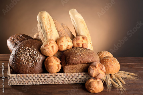 Lot of different bread in a basket on a wooden table