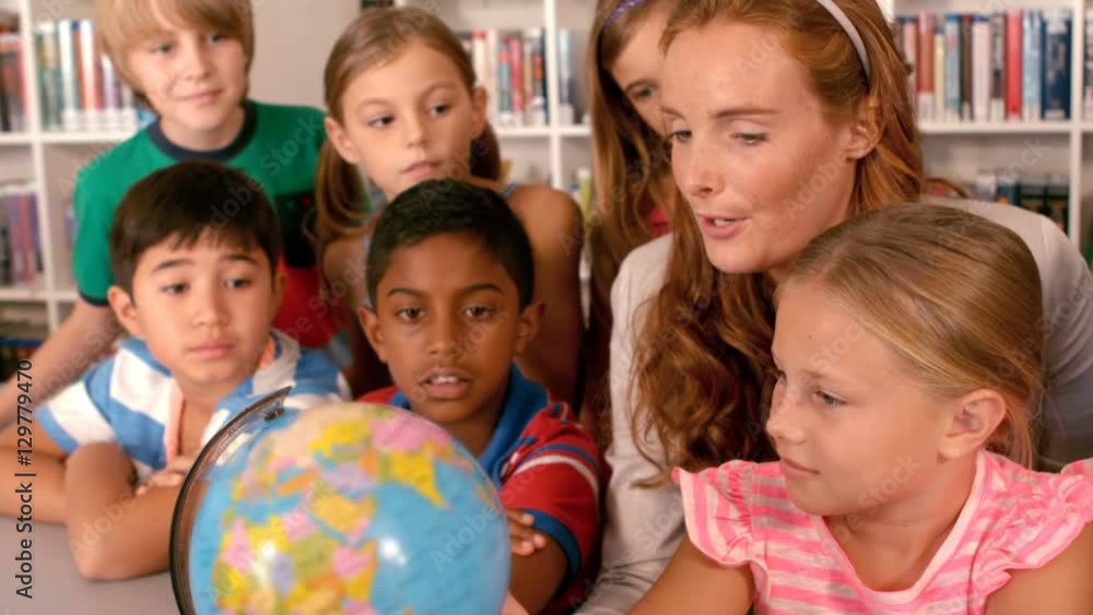 Teacher and schoolkids studying globe in library Teacher and schoolkids studying globe in library