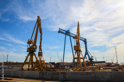 Beautiful landscape of cranes in shipyard against a backlight in coast of Huelva, Andalusia, Spain.